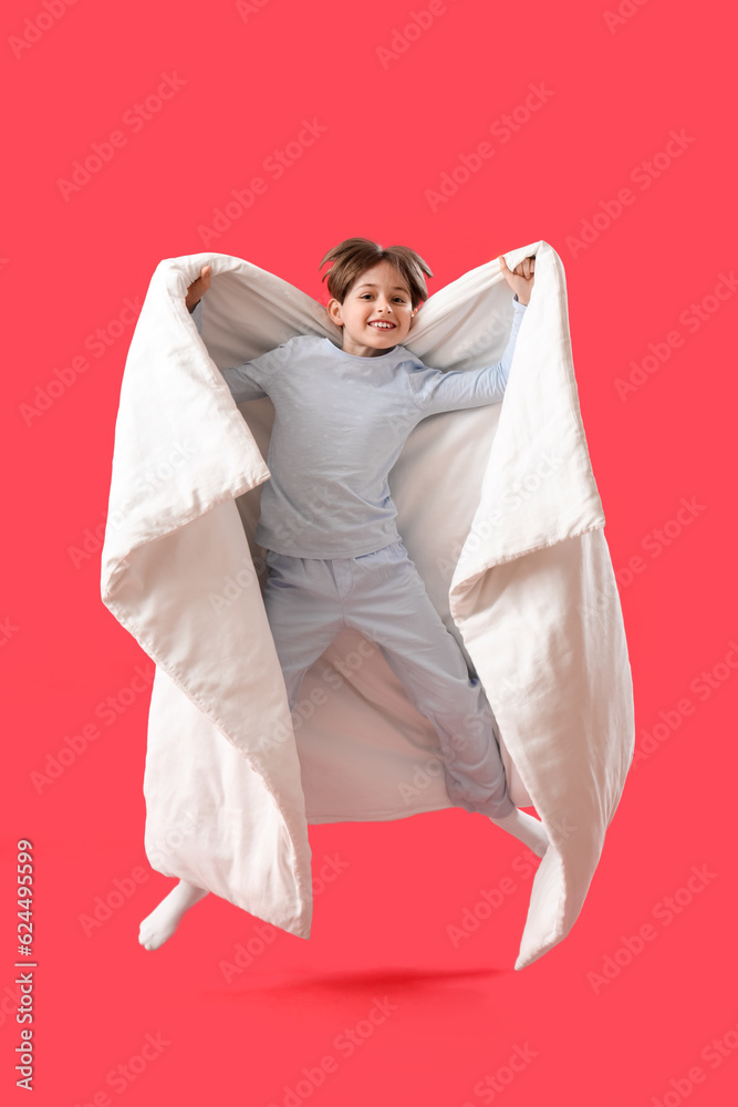 Jumping little boy with blanket on red background