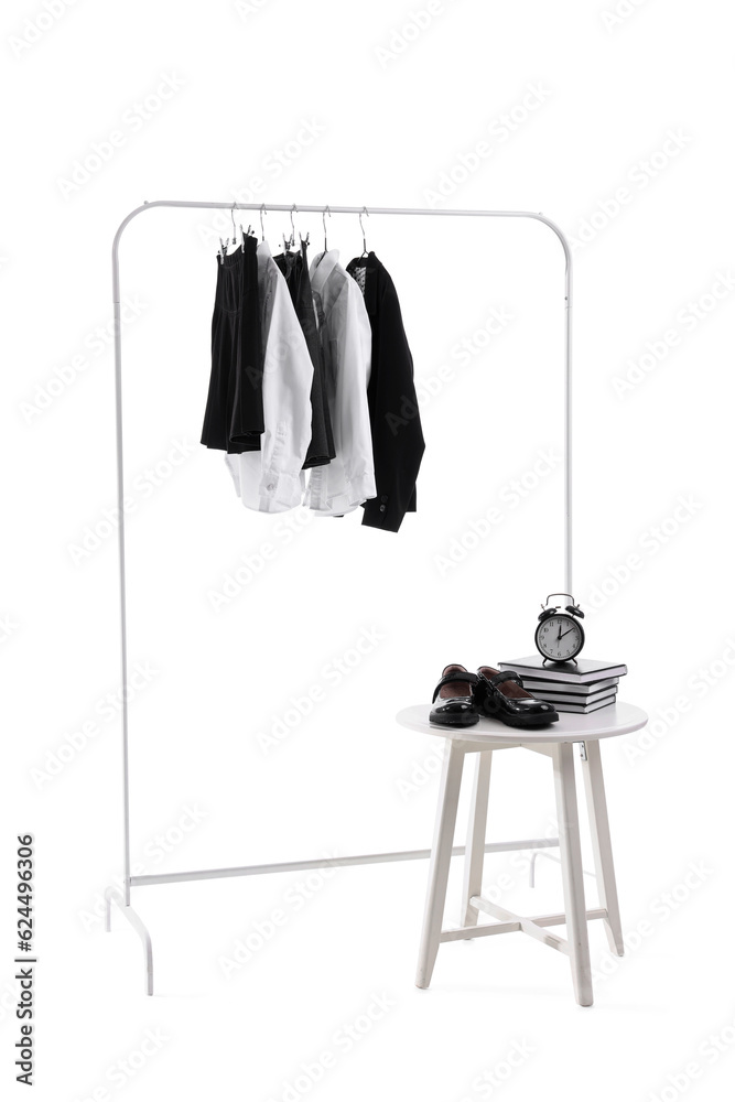 Rack with stylish school uniform, chair, books, shoes and alarm clock on white background