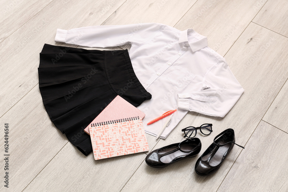 Composition with stylish school uniform, shoes, eyeglasses and stationery on wooden background