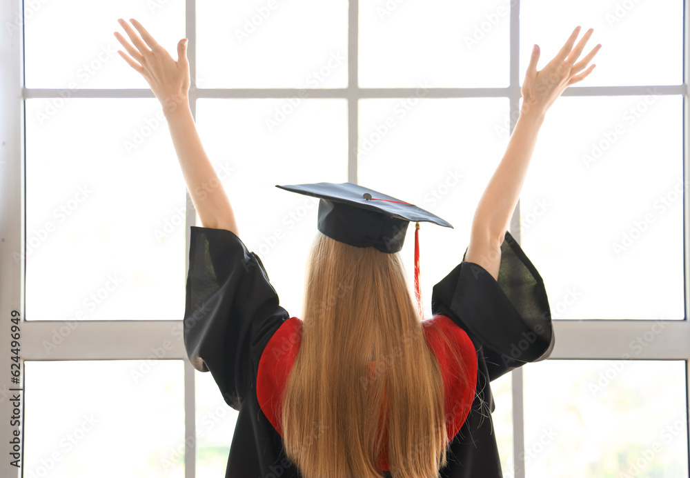 Female graduate student near window in room, back view