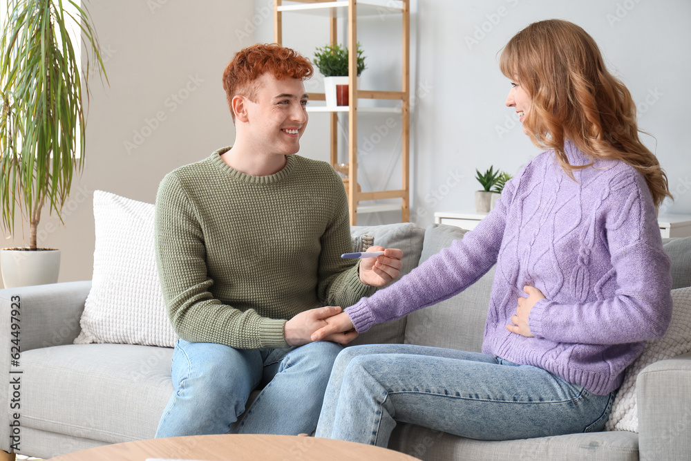 Happy young couple with pregnancy test at home