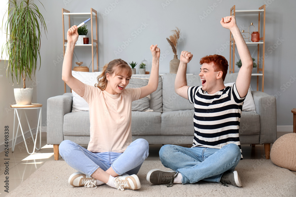 Happy young couple with pregnancy test at home