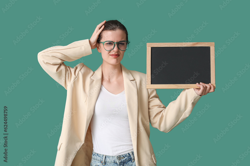 Stressed female teacher with chalkboard on green background