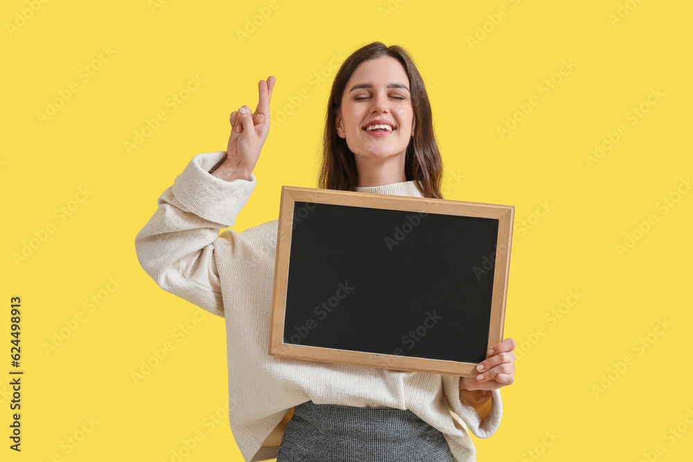 Female teacher with chalkboard pointing at something on yellow background