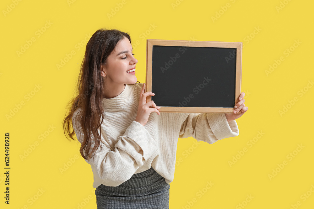 Female teacher with chalkboard on yellow background