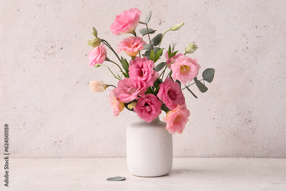 Vase with beautiful pink eustoma flowers and eucalyptus on white background