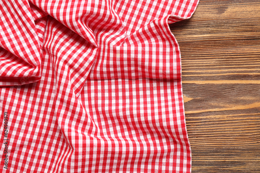 Red checkered napkin on wooden background, closeup