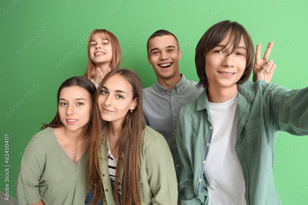 Group of teenage students taking selfie on green background