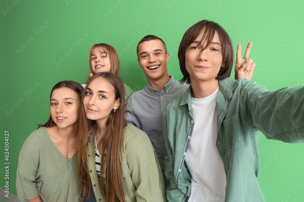 Group of teenage students taking selfie on green background