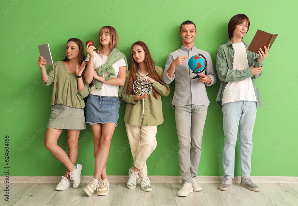 Group of teenage students near green wall