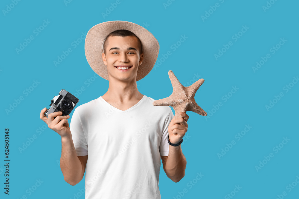 Teenage boy with photo camera and starfish on blue background