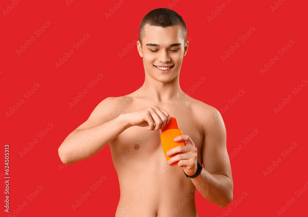 Teenage boy with sunscreen cream on red background