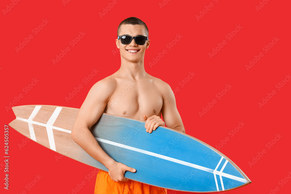 Teenage boy with surfboard on red background