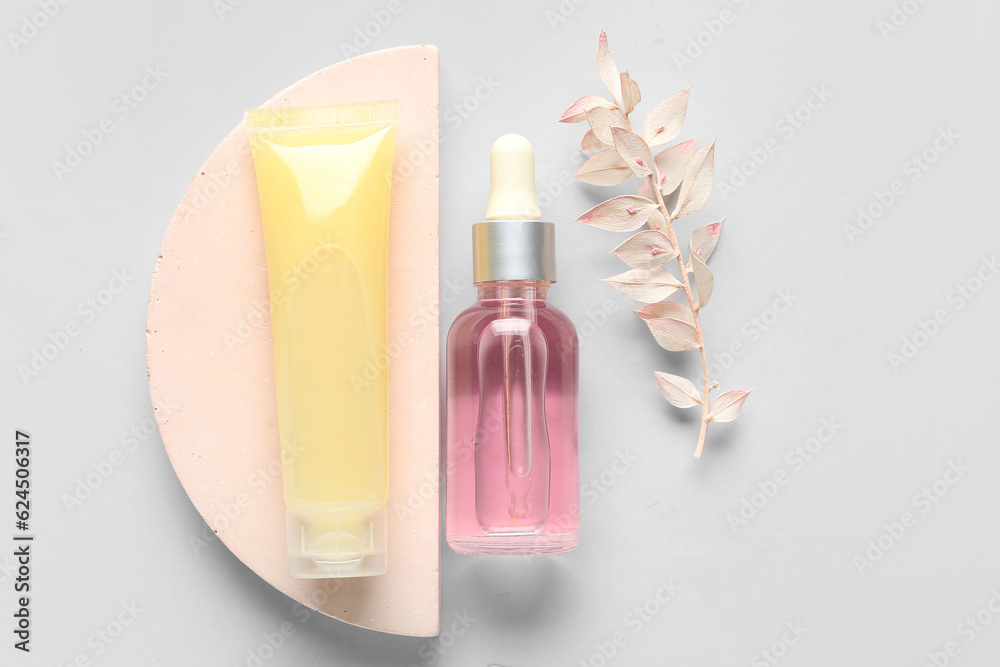 Composition with cosmetic products, plaster podium and dried plant on light background