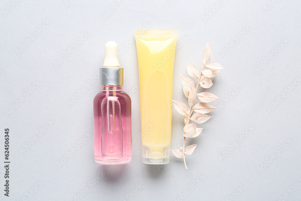 Cosmetic products and dried plant on light background