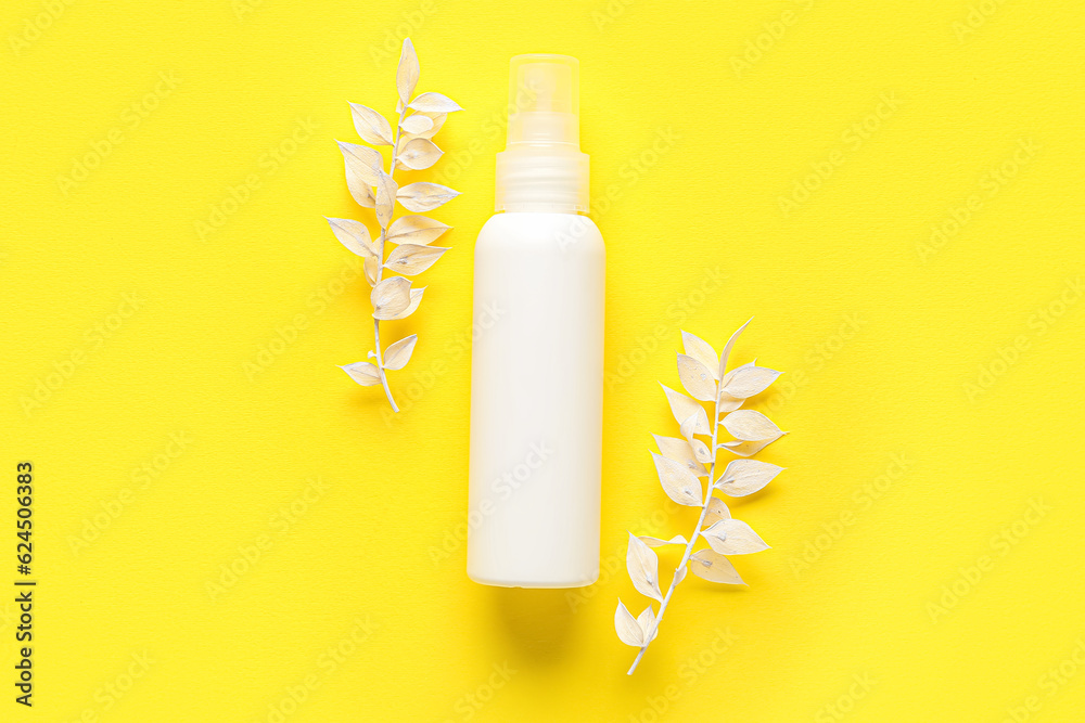 Composition with bottle of cosmetic product and dried plants on yellow background