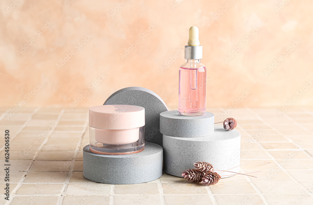 Composition with cosmetic products, podiums and dried flowers on light tile table