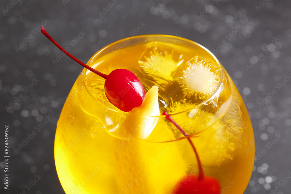 Glass of tasty cocktail with maraschino cherries on grey background