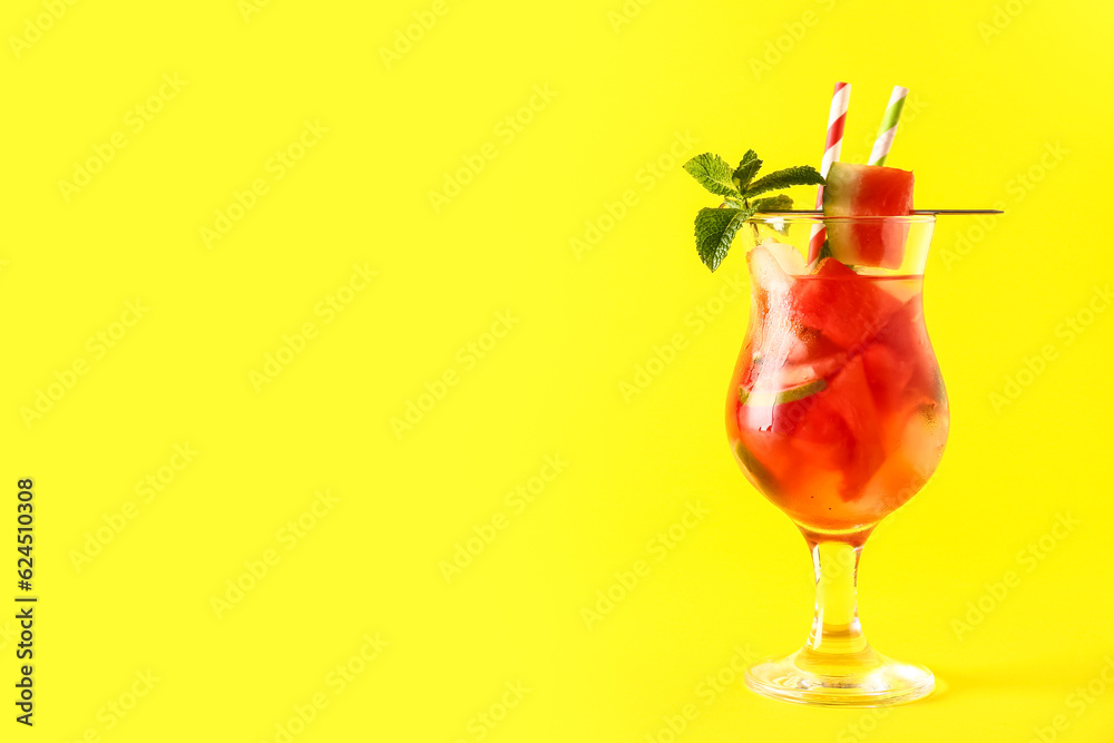 Glass of fresh watermelon lemonade with lime and mint on yellow background