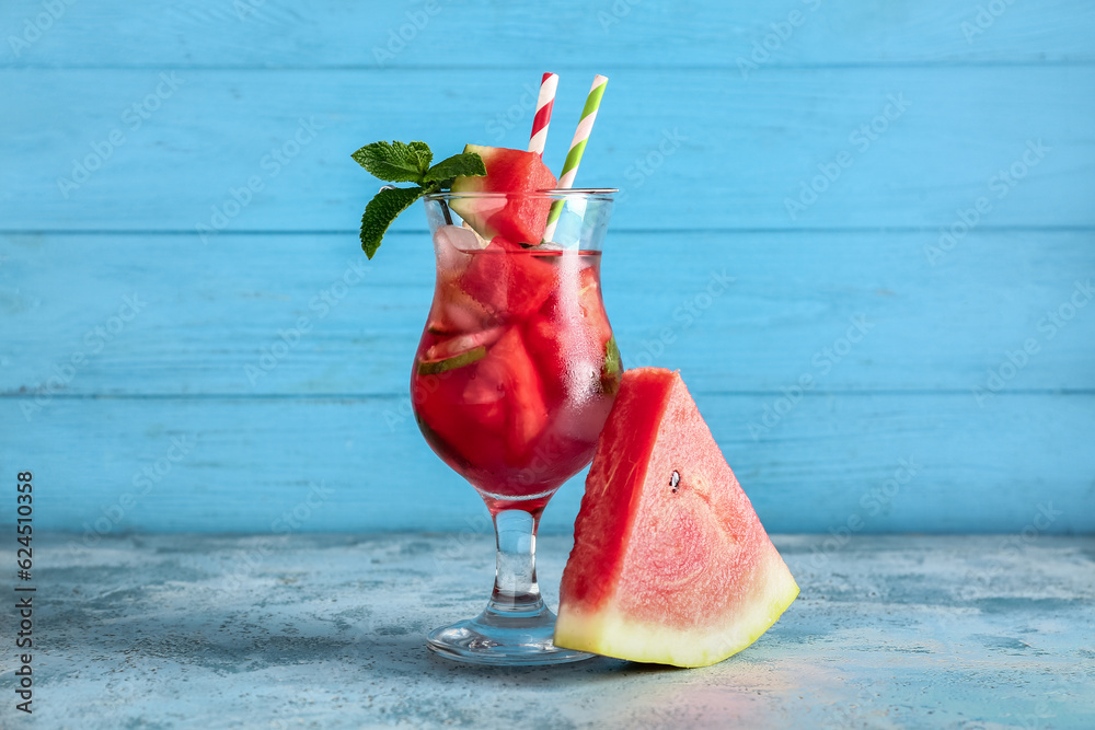 Glass of fresh watermelon lemonade with mint on blue table