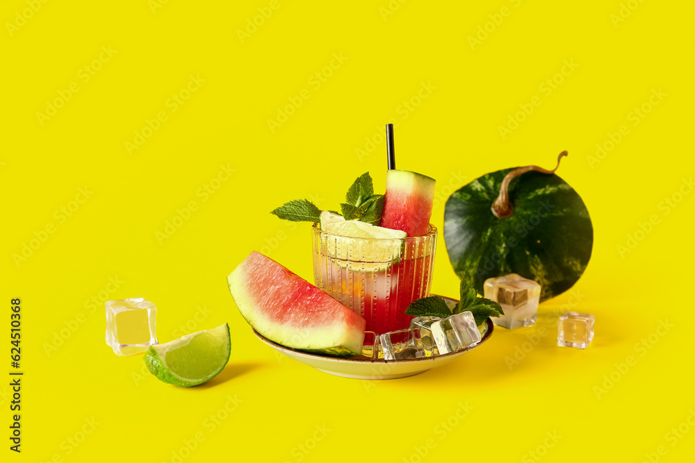 Glass of fresh watermelon lemonade with lime and mint on yellow background