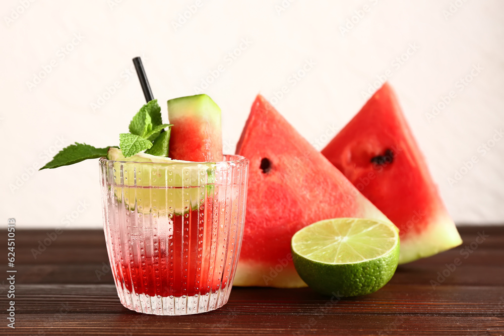 Glass of fresh watermelon lemonade with lime and mint on wooden table