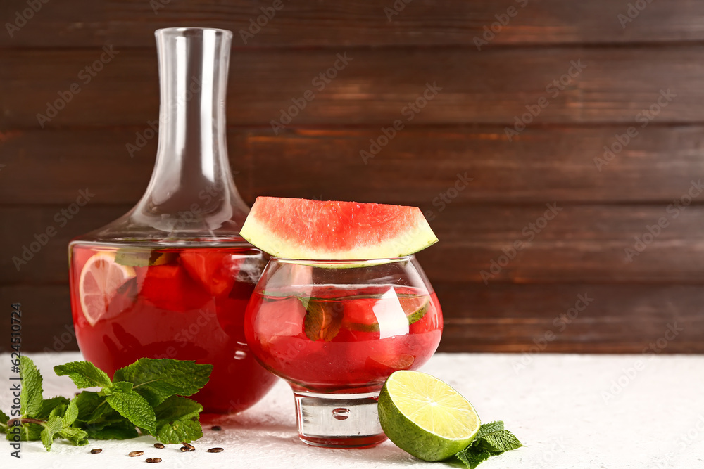 Glass and bottle of fresh watermelon lemonade with lime on white table