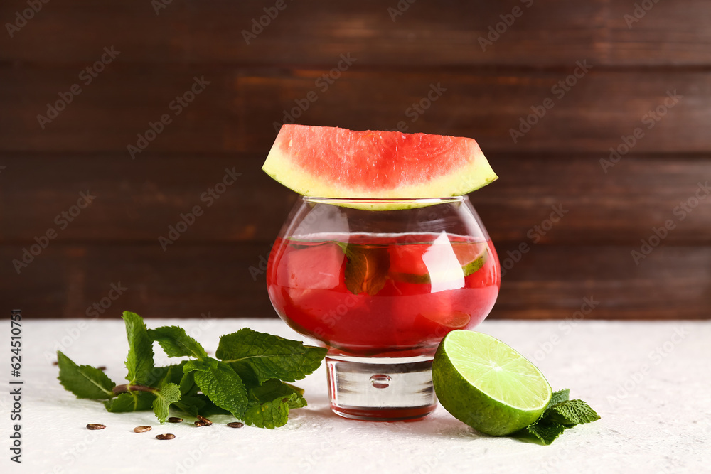 Glass of fresh watermelon lemonade with lime and mint on white table