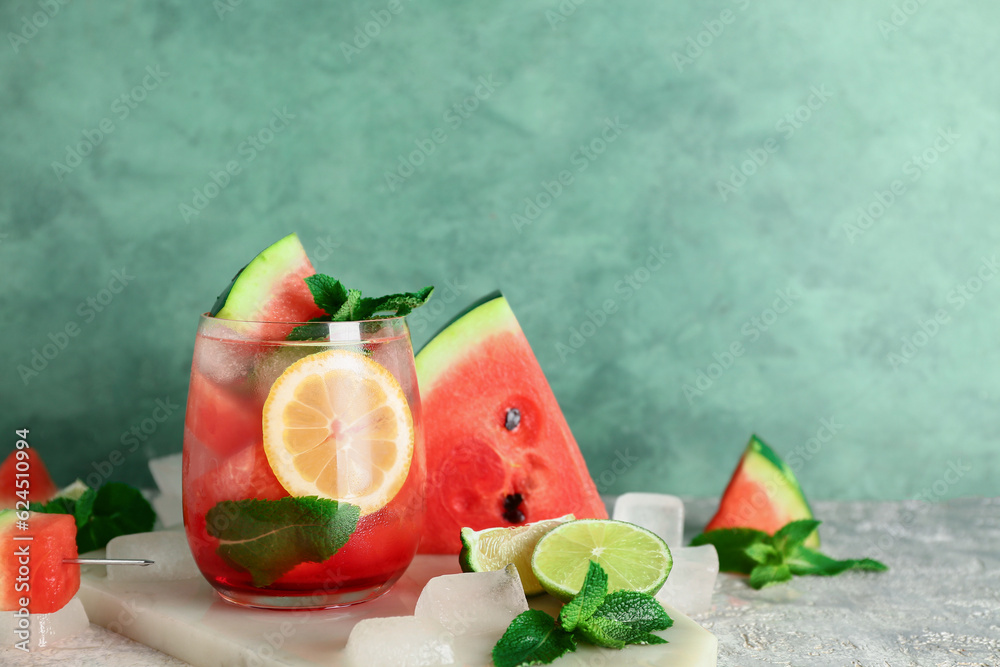 Board with glass of fresh watermelon lemonade and mint on grey table