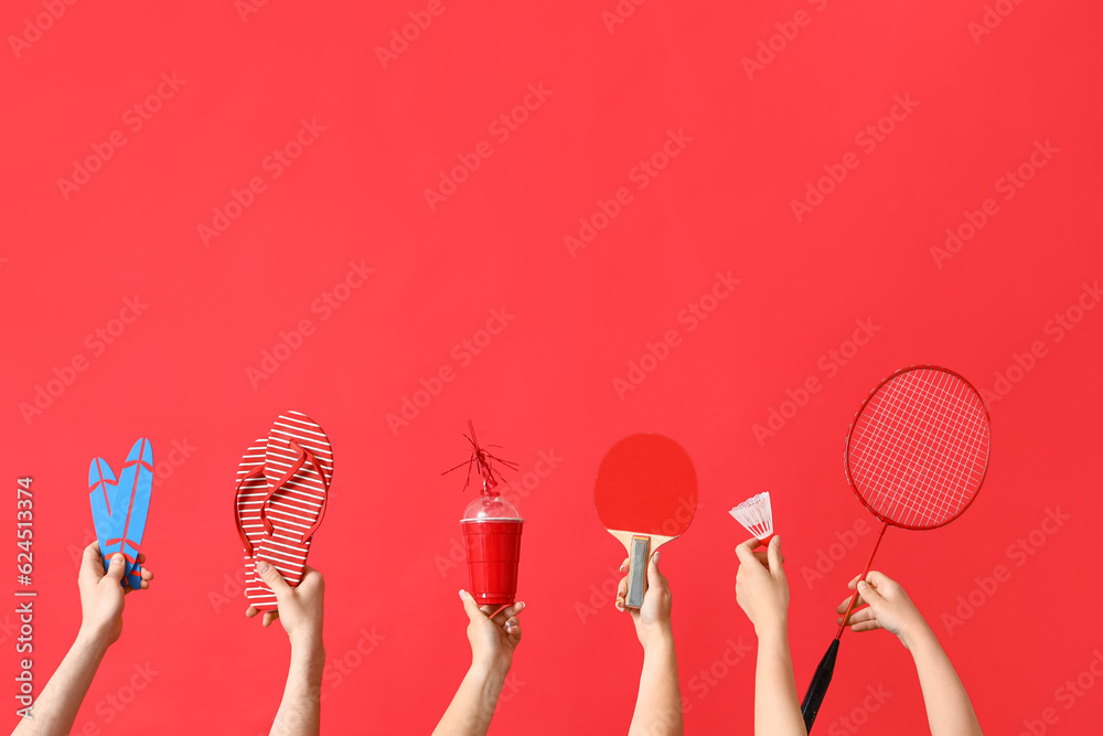 Many hands with beach accessories and sport equipment on red background