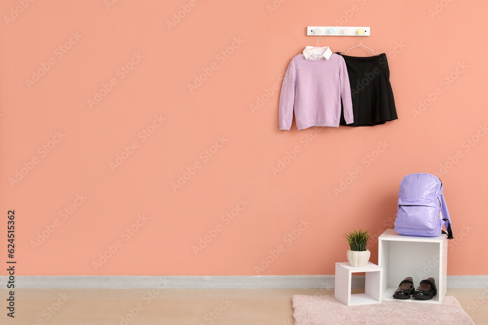 Shelves with backpack, shoes and stylish school uniform hanging on beige wall in room