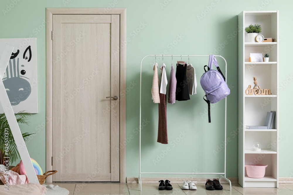 Stylish school uniform and backpack hanging on rack in childrens room