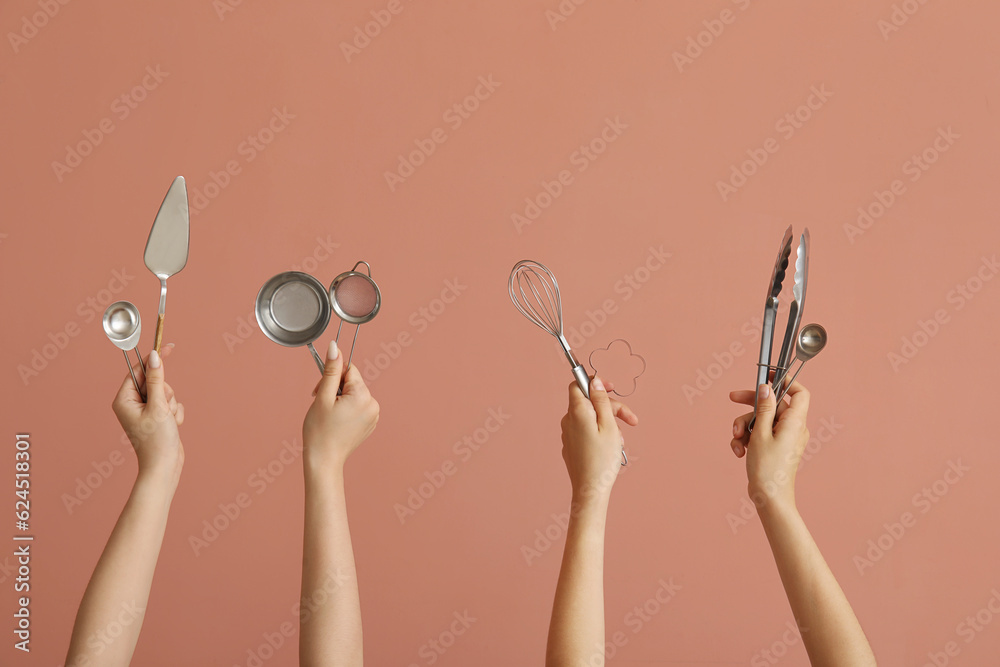 Female hands with baking utensils on pink background