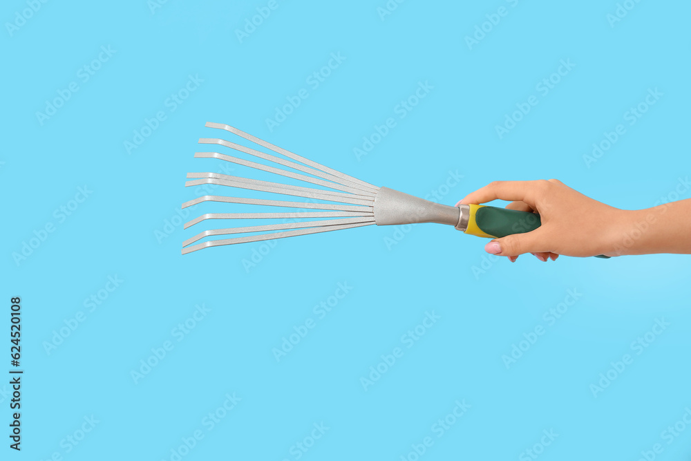 Woman with gardening rake on blue background