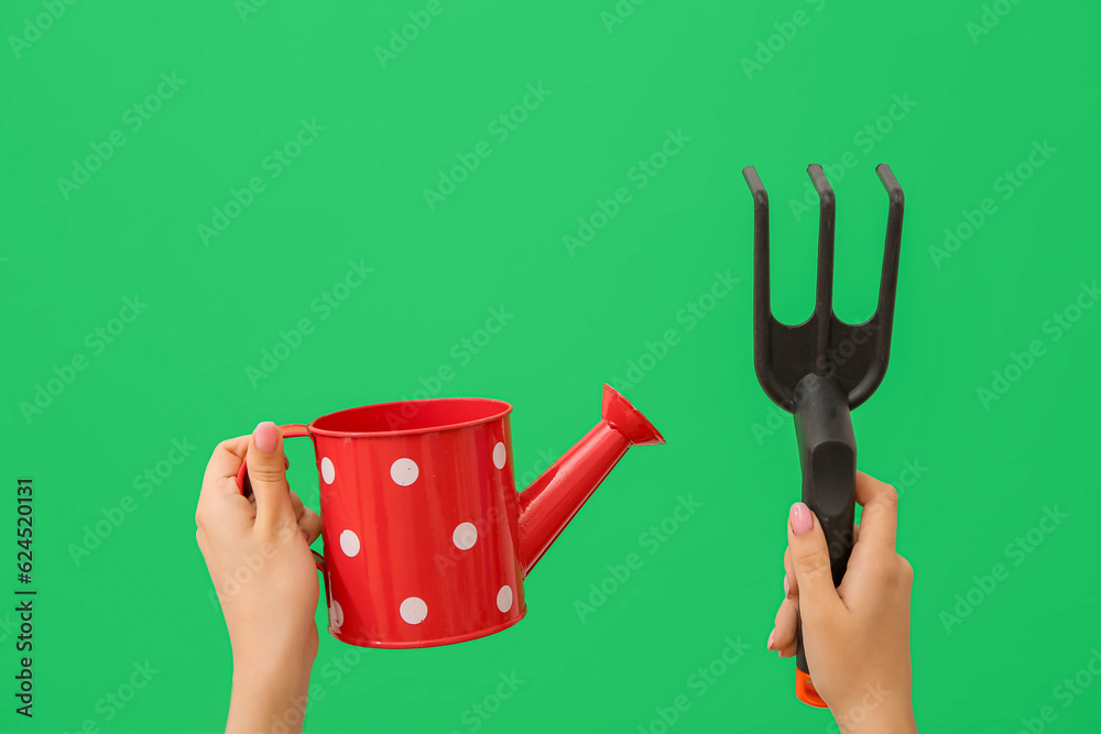 Woman with gardening rake and watering can on green background