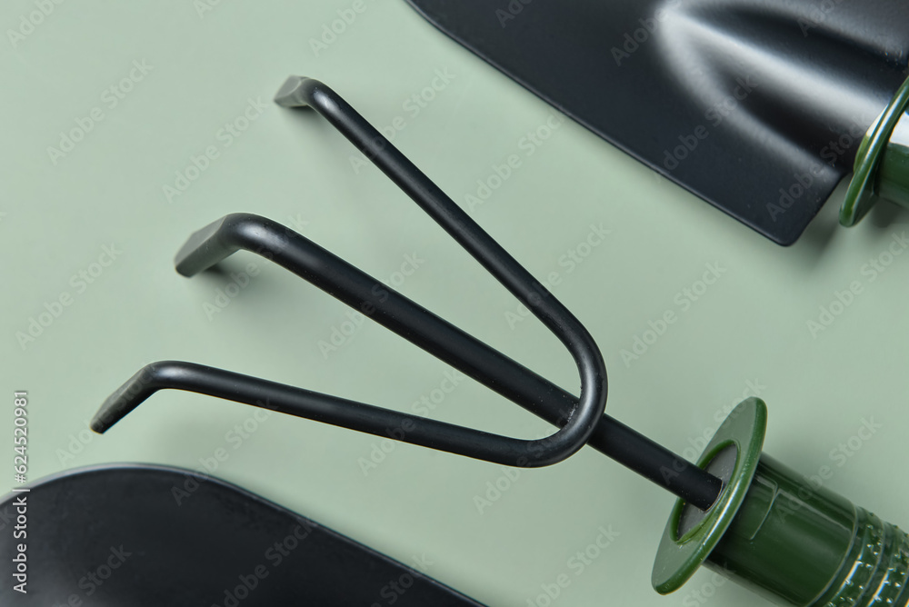 Gardening rake on green background, closeup