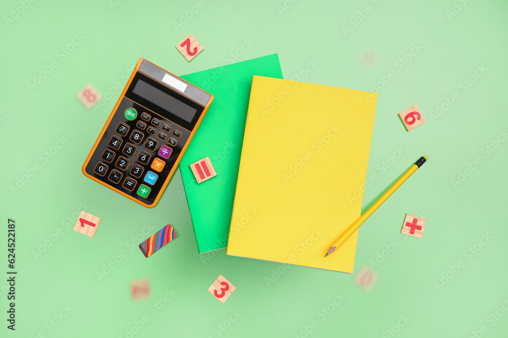 Calculator and notebooks with pencil on green background