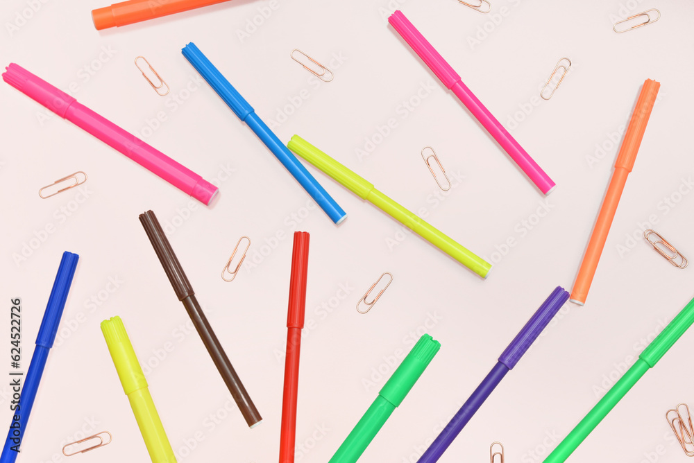 Colorful felt-tip pens and paperclips on pink background