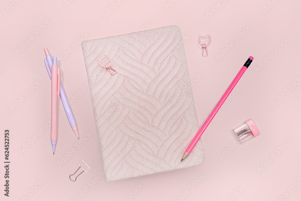 Notebook, pencil and pens on pink background