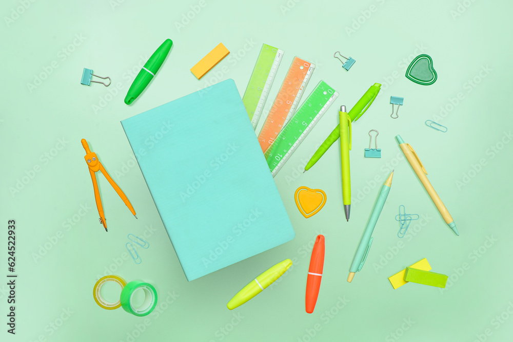 Composition with notebook and school stationery on green background