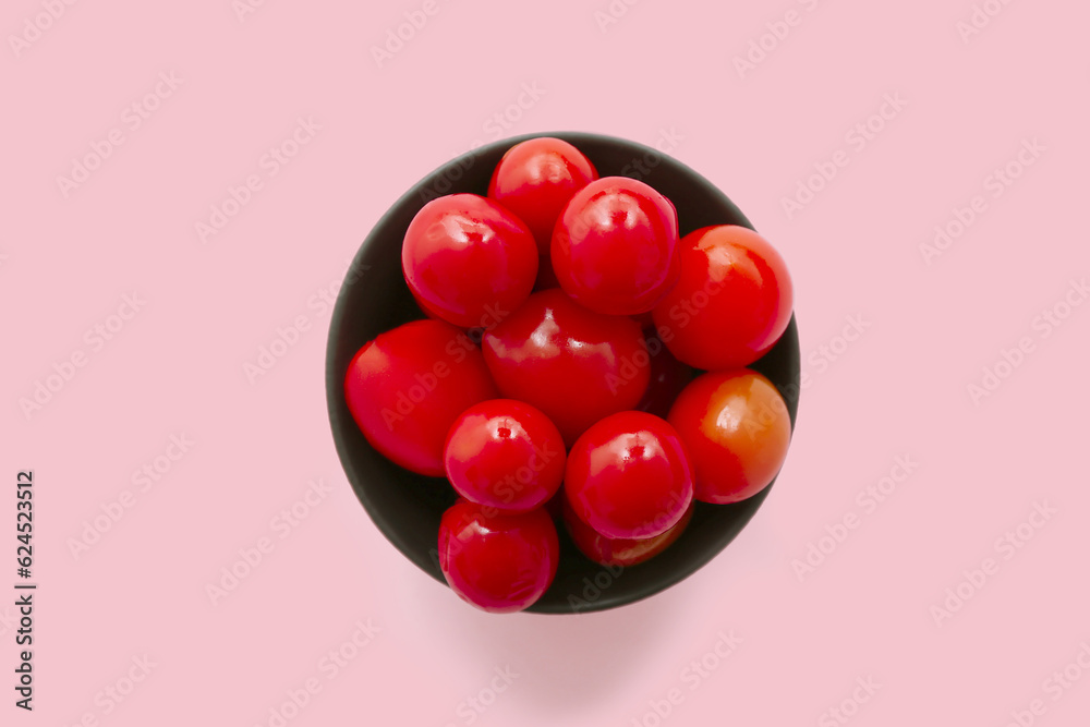 Bowl with canned tomatoes on pink background