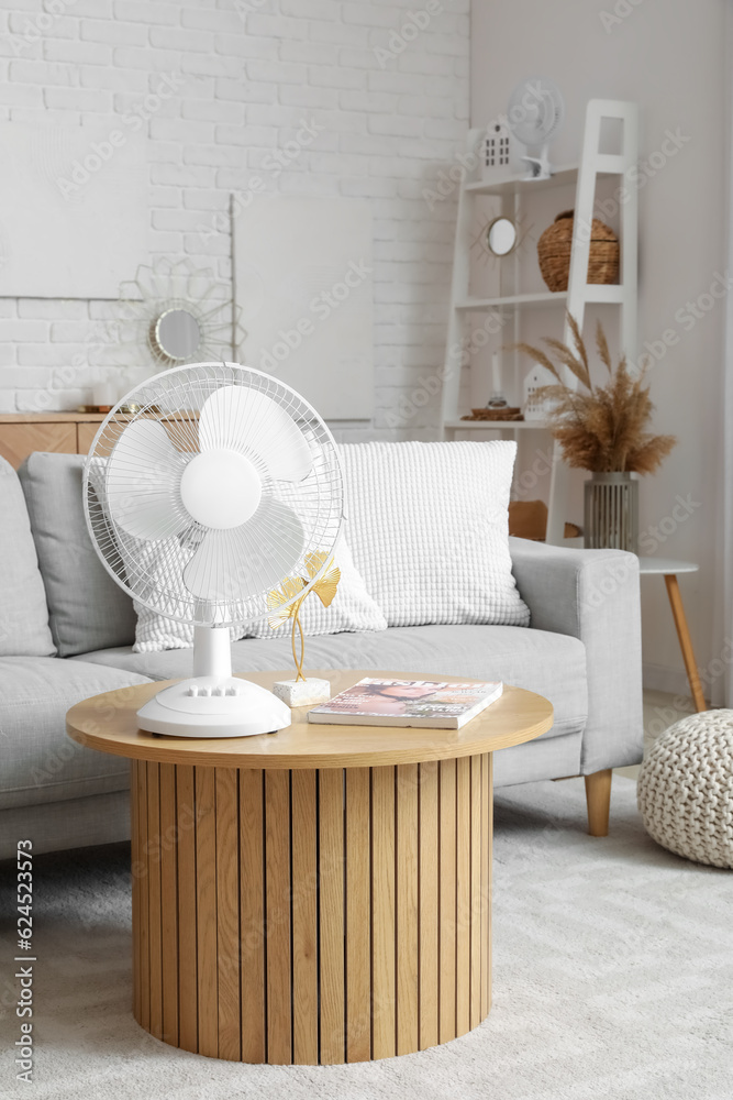 Interior of light living room with modern fan on coffee table