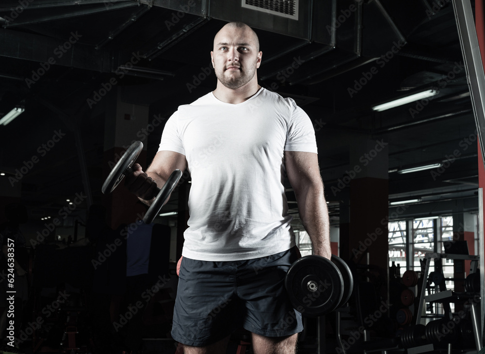 Male bodybuilder engaged with dumbbells in the gym