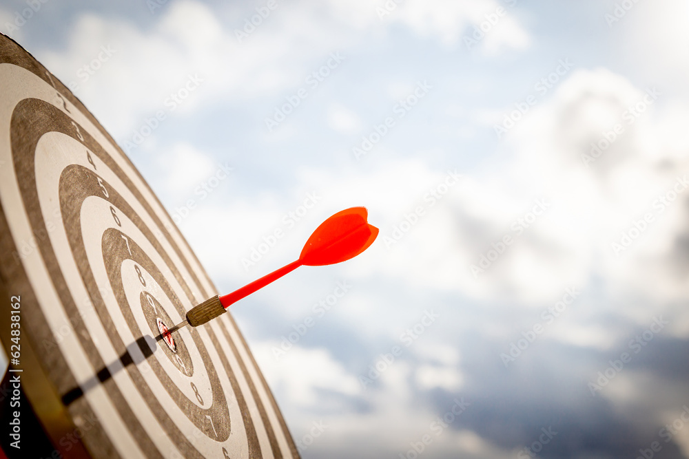 Close up shot red darts arrows in the target  of dartboard center on dark blue sky background. Busin