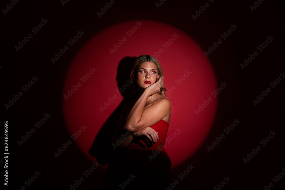 Fashion, spotlight and red with a model woman in studio on a dark background for classy elegance or 