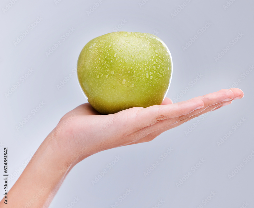 Vegan, hand and apple with water drops, nutrition and clean against a grey studio background. Zoom, 