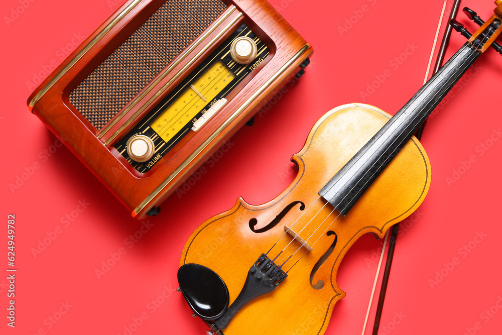 Violin and retro radio receiver on color background