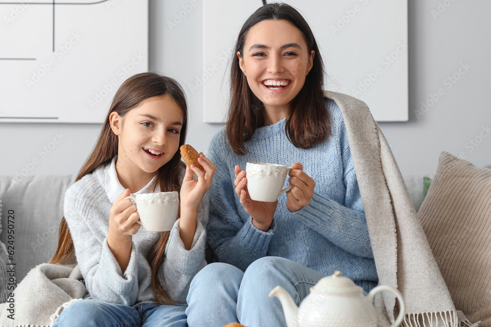 Little girl with her mother drinking tea at home