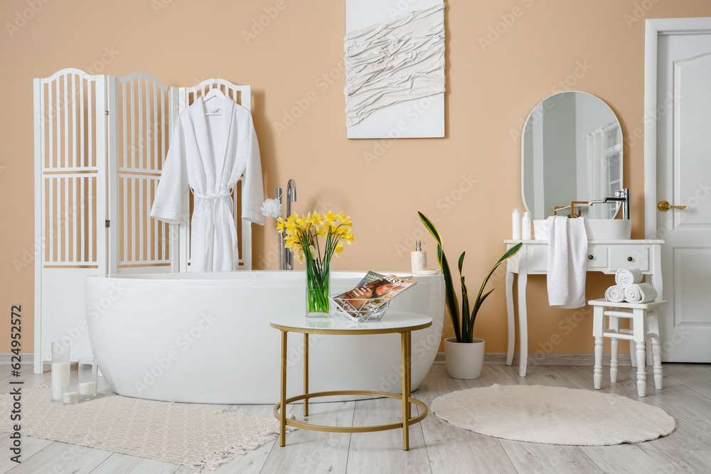 Interior of bathroom with bathtub, dressing table and narcissus flowers