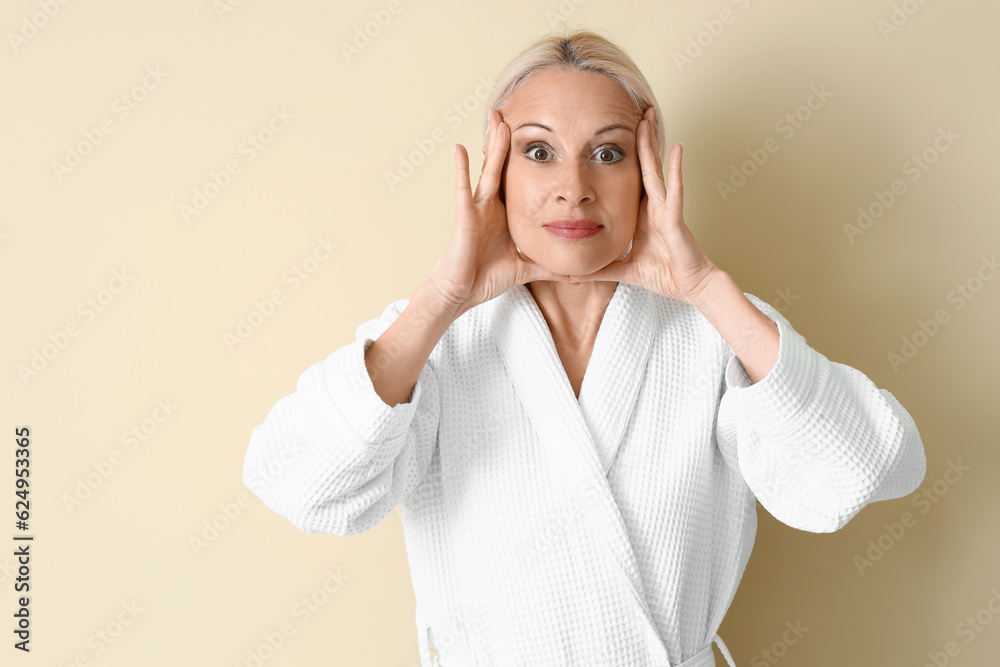 Mature woman doing face building exercise on beige background